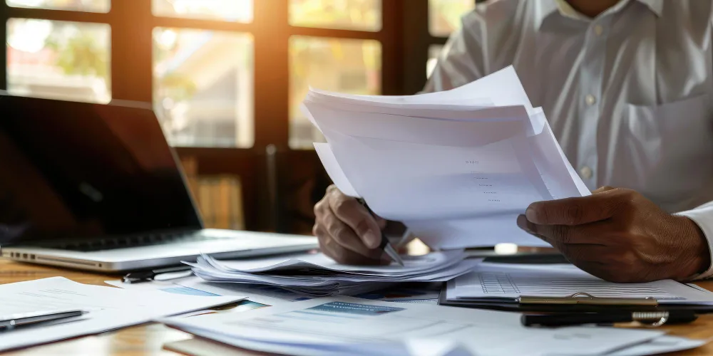 Homem analisando documentos, importante para cuidados ao comprar imóvel em leilão.